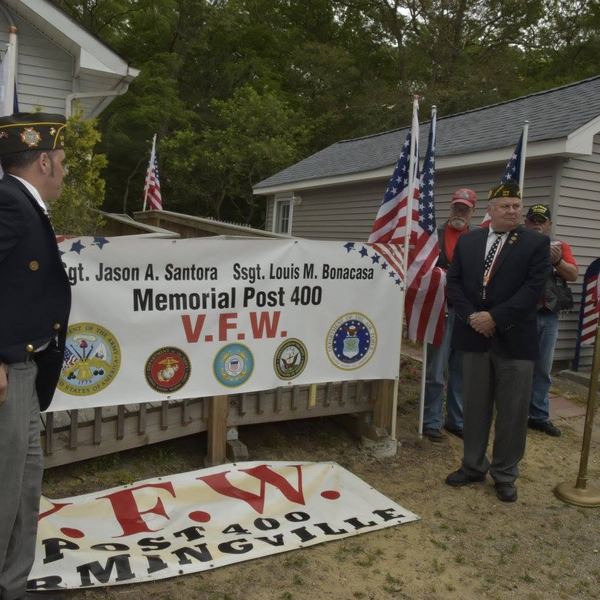 Veterans at a podium in front of the memorial banner