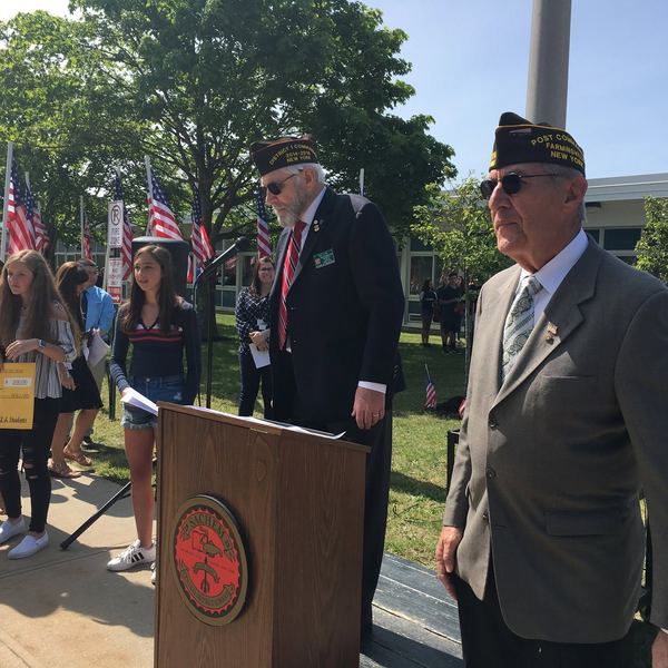 Veterans speaking at a podium beside flags
