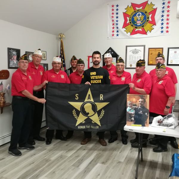 Members holding a black flag that reads Honor the Fallen