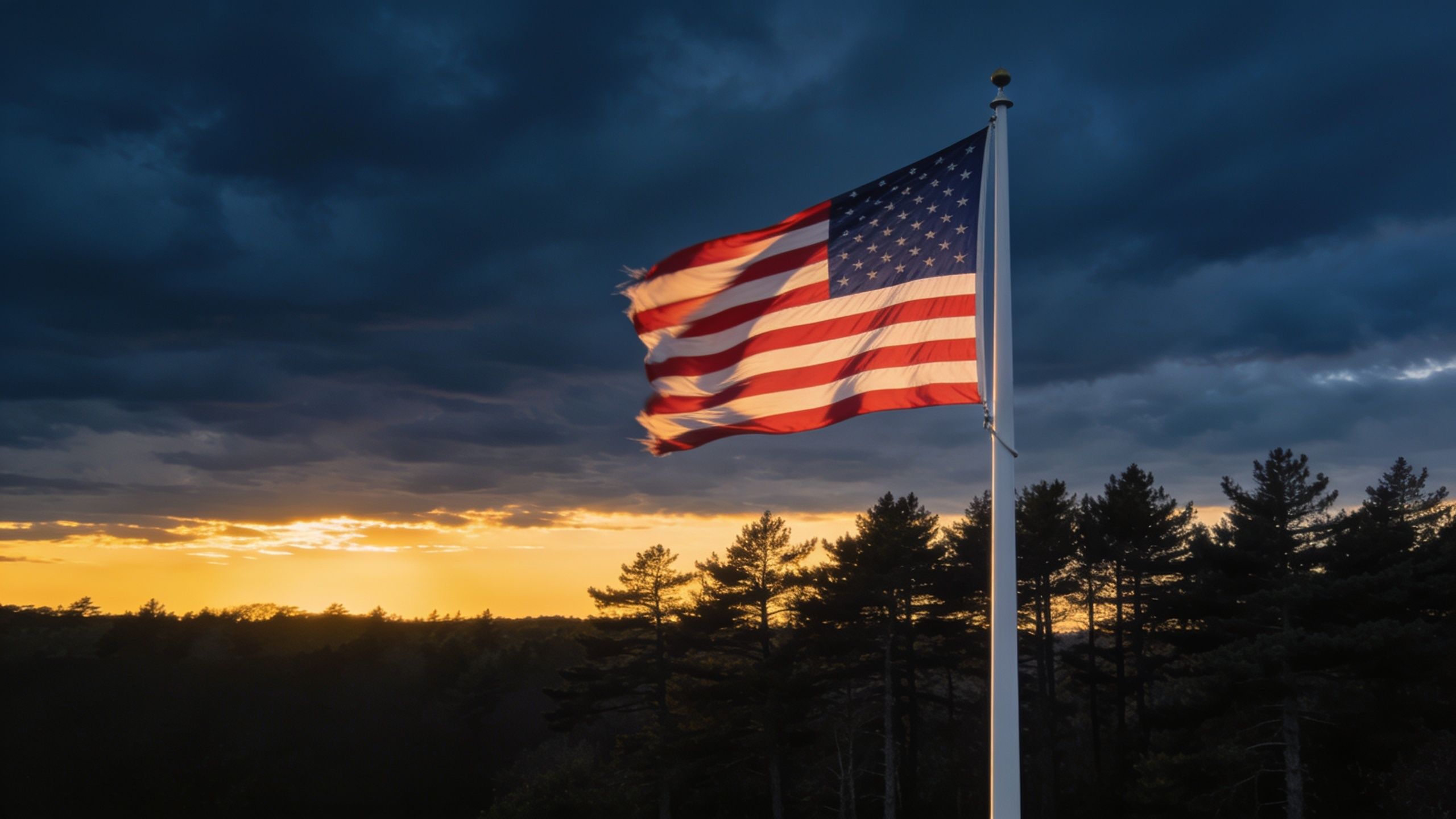 An American flag flying at dusk over pine trees